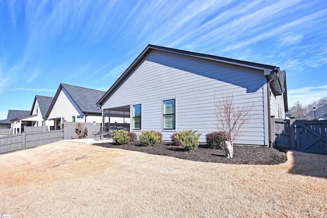 view of property exterior featuring a gate, a patio area, and fence