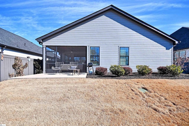 rear view of house featuring a patio, a lawn, fence, and a sunroom