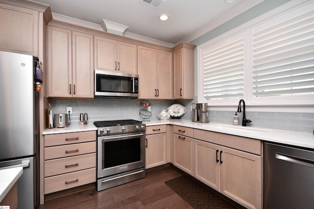 kitchen featuring stainless steel appliances, a sink, light countertops, backsplash, and light brown cabinetry