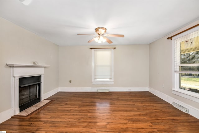 unfurnished living room featuring baseboards, a fireplace with flush hearth, visible vents, and wood finished floors