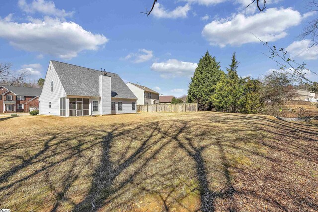 back of property with a yard, a chimney, fence, and a sunroom