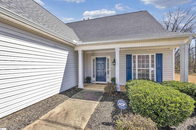 doorway to property featuring a shingled roof and a porch