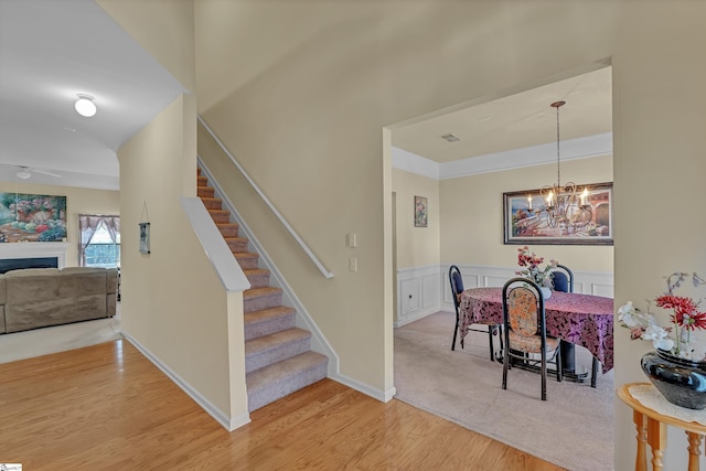 stairs featuring a decorative wall, a wainscoted wall, a fireplace, wood finished floors, and visible vents