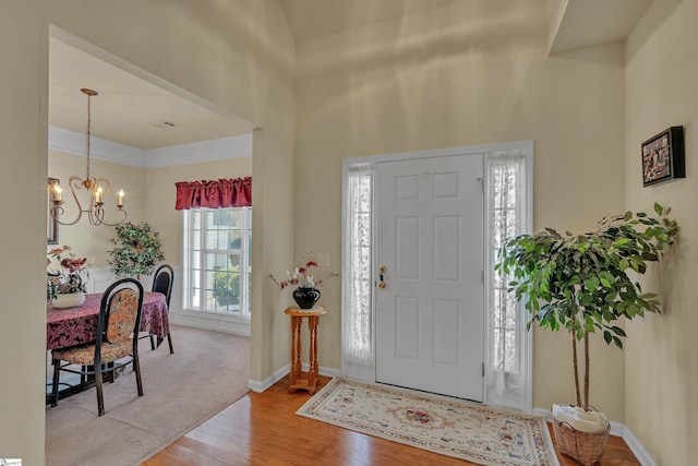 foyer with a chandelier, baseboards, and wood finished floors