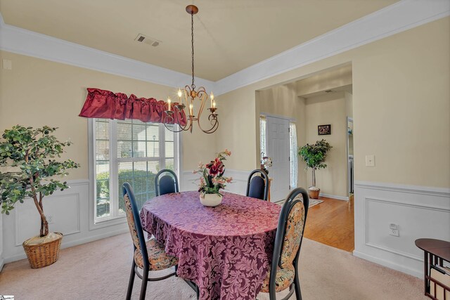 dining area featuring ornamental molding, wainscoting, visible vents, and a notable chandelier