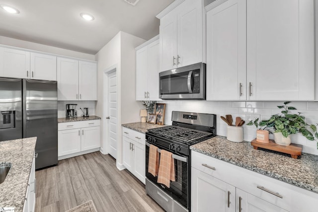 kitchen with light wood-style floors, white cabinetry, appliances with stainless steel finishes, and decorative backsplash