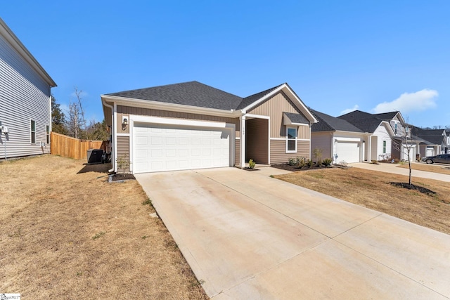 ranch-style house featuring a garage, concrete driveway, roof with shingles, fence, and board and batten siding