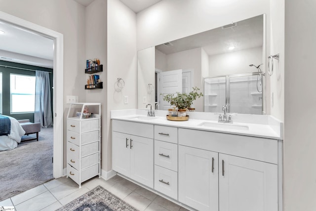 ensuite bathroom featuring a stall shower, double vanity, a sink, and tile patterned floors