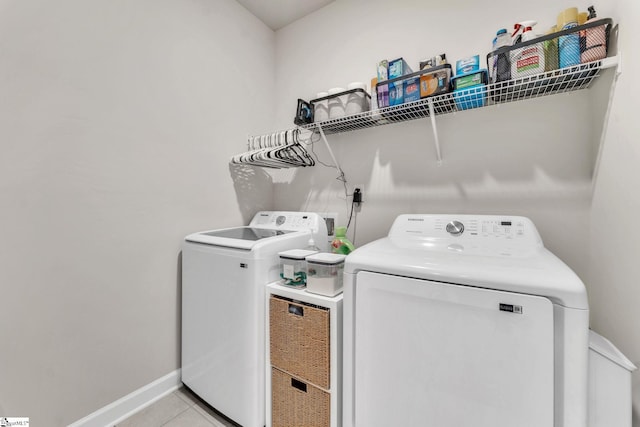 laundry area with laundry area, separate washer and dryer, light tile patterned flooring, and baseboards