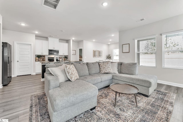 living room featuring a wealth of natural light, light wood-type flooring, and visible vents