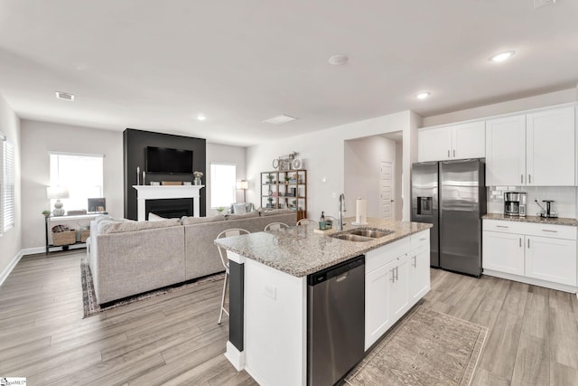 kitchen with visible vents, decorative backsplash, appliances with stainless steel finishes, light wood-type flooring, and a sink