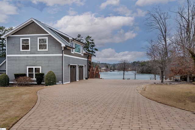 view of side of property featuring decorative driveway and a water view