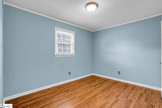 spare room with ornamental molding, baseboards, light wood-style flooring, and a textured ceiling