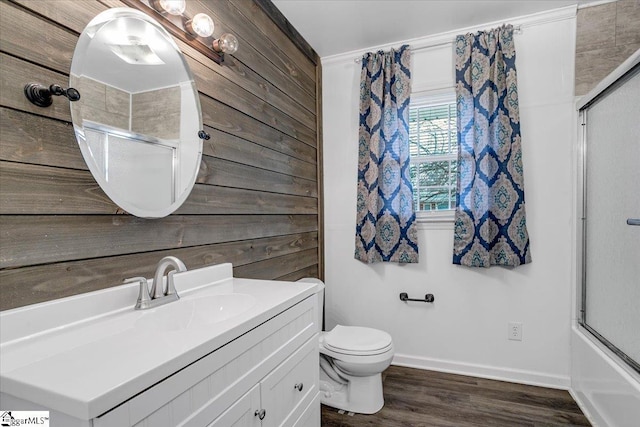 full bath with toilet, wood walls, vanity, wood finished floors, and baseboards