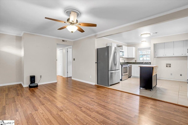 kitchen featuring stainless steel appliances, ornamental molding, light wood-type flooring, and baseboards