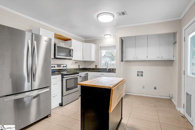 kitchen with visible vents, butcher block countertops, stainless steel appliances, crown molding, and a sink