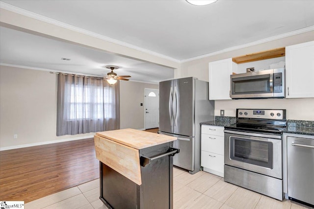 kitchen featuring light wood-style flooring, appliances with stainless steel finishes, ornamental molding, white cabinetry, and ceiling fan