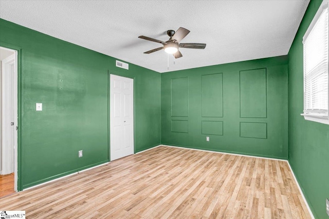 spare room with visible vents, baseboards, ceiling fan, a textured ceiling, and light wood-style floors