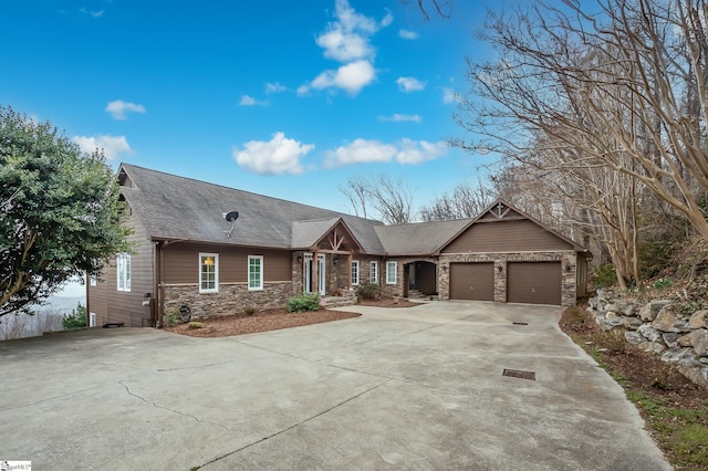 view of front of home with a garage, concrete driveway, a shingled roof, and stone siding