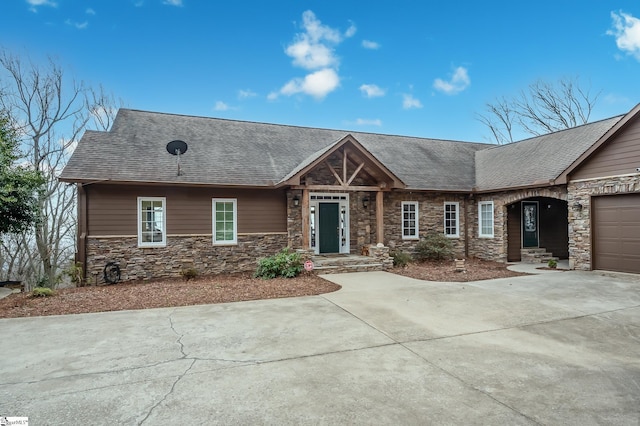 view of front of home featuring a garage, stone siding, a shingled roof, and driveway