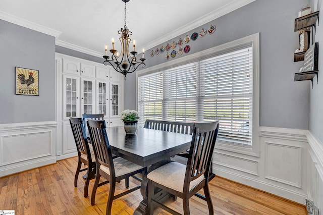 dining area with a chandelier, a wainscoted wall, light wood-style flooring, and crown molding