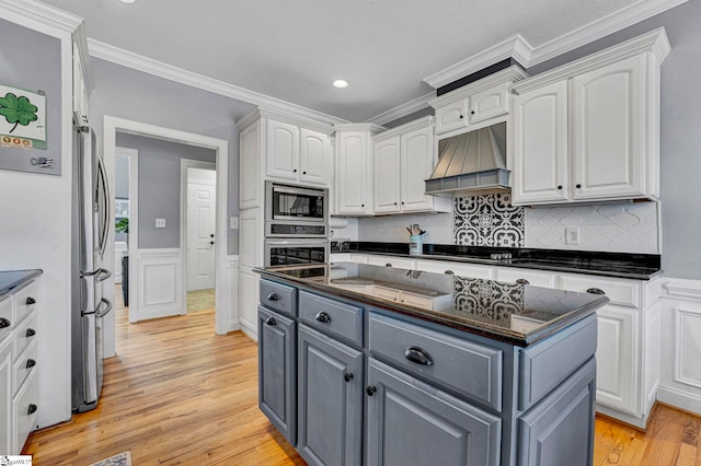 kitchen featuring light wood-style flooring, appliances with stainless steel finishes, custom exhaust hood, gray cabinetry, and white cabinetry