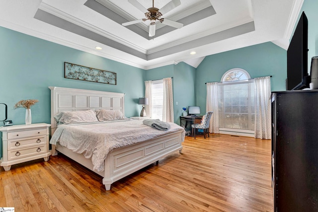 bedroom with ornamental molding, a tray ceiling, and light wood-style flooring