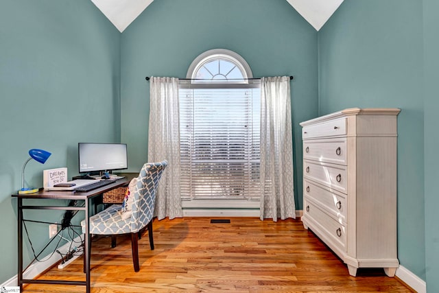 office space featuring light wood-type flooring, vaulted ceiling, and baseboards