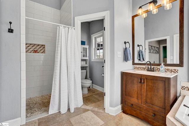 bathroom with toilet, baseboards, a tile shower, and vanity