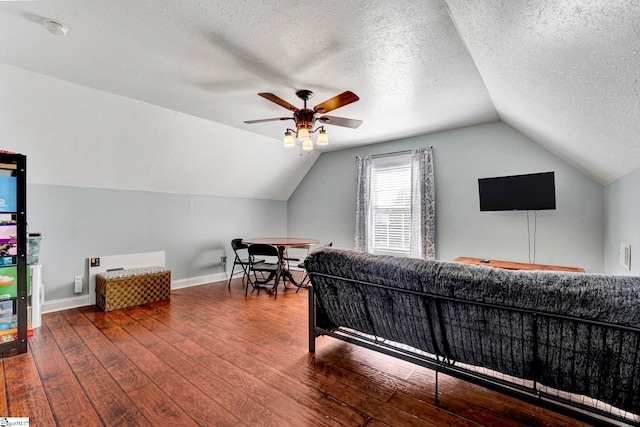 bedroom with ceiling fan, vaulted ceiling, a textured ceiling, baseboards, and hardwood / wood-style flooring