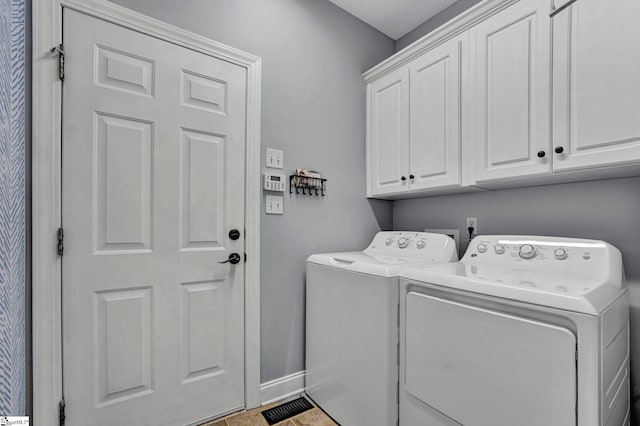 clothes washing area with cabinet space, baseboards, and washing machine and clothes dryer