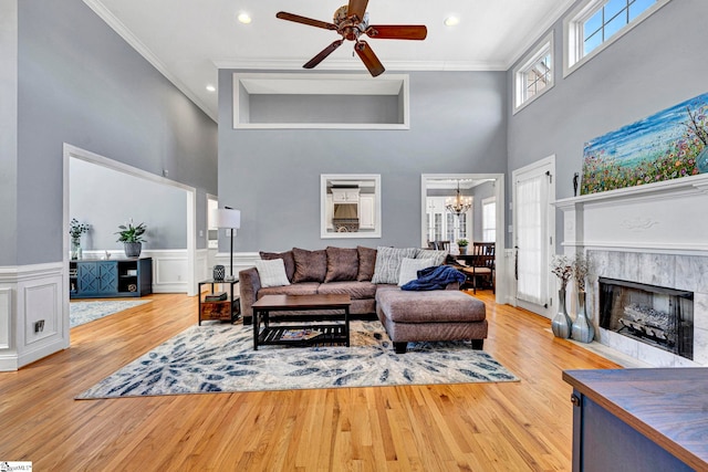 living area with a wainscoted wall, ornamental molding, a tiled fireplace, and wood finished floors