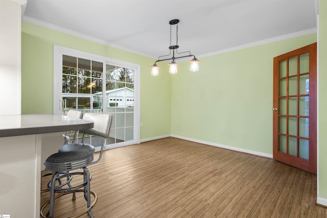 dining space with ornamental molding, baseboards, and wood finished floors