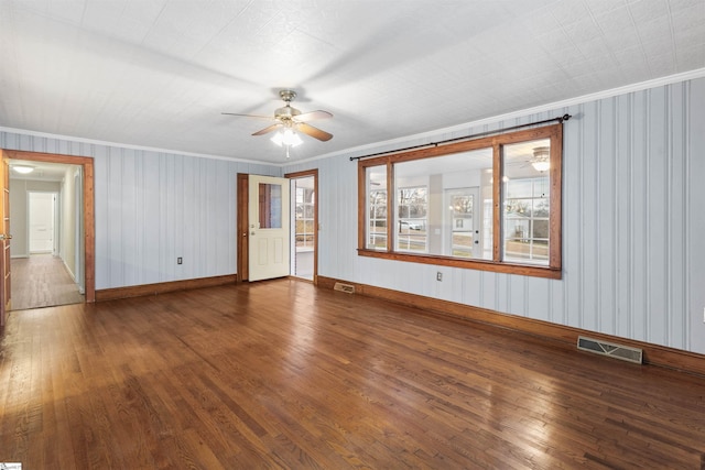 unfurnished room with wood-type flooring, visible vents, baseboards, and ornamental molding