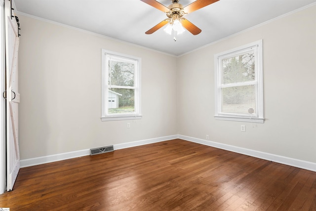 empty room with a barn door, baseboards, visible vents, ceiling fan, and wood finished floors