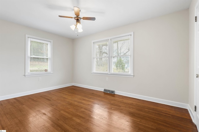 spare room with a wealth of natural light, baseboards, visible vents, and hardwood / wood-style floors