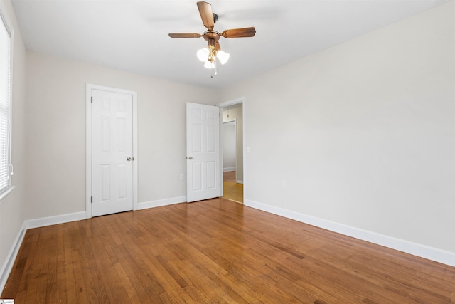 unfurnished bedroom featuring hardwood / wood-style flooring, baseboards, and a ceiling fan