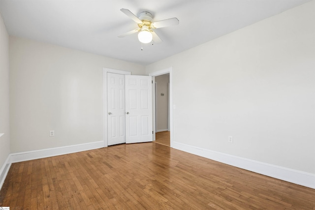 empty room featuring a ceiling fan, baseboards, and hardwood / wood-style floors