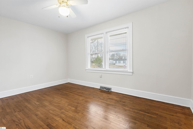 spare room with ceiling fan, baseboards, visible vents, and dark wood finished floors