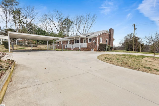 view of front of home with a porch, brick siding, driveway, and a chimney