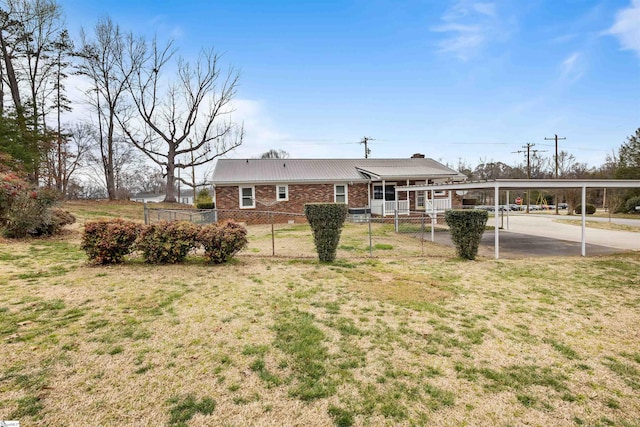 view of front facade with metal roof, brick siding, a front yard, and fence