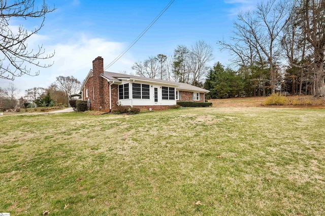 exterior space with brick siding, a yard, and a chimney