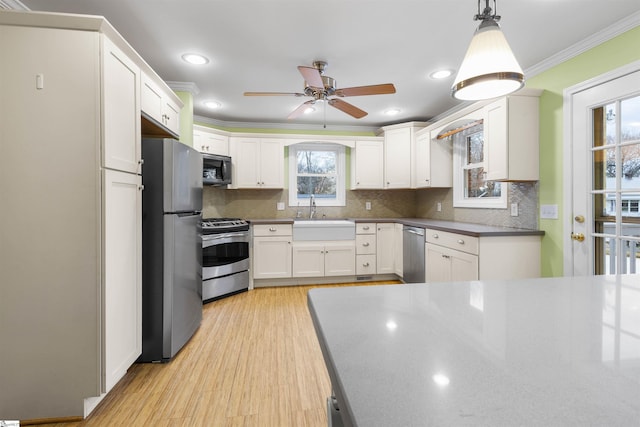 kitchen with white cabinetry, ornamental molding, stainless steel appliances, and a sink