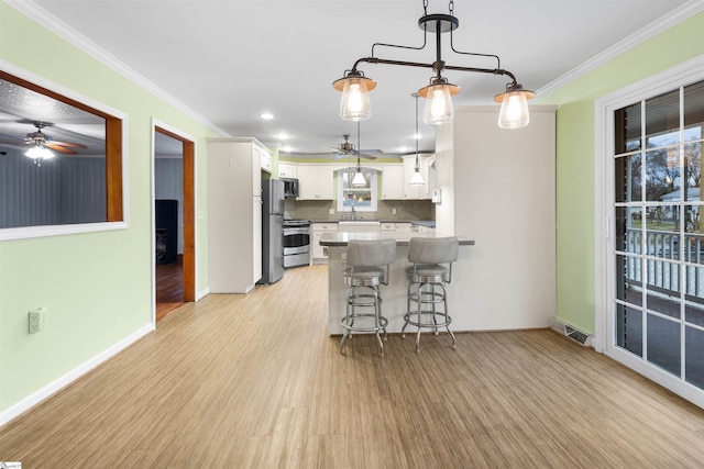 kitchen featuring stainless steel appliances, white cabinets, ornamental molding, and a kitchen breakfast bar