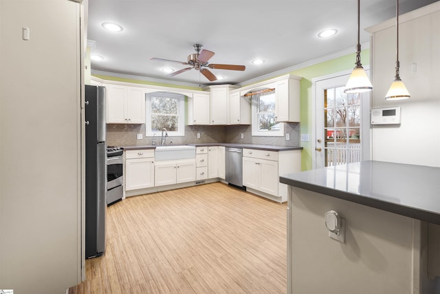 kitchen featuring crown molding, dark countertops, backsplash, appliances with stainless steel finishes, and a sink