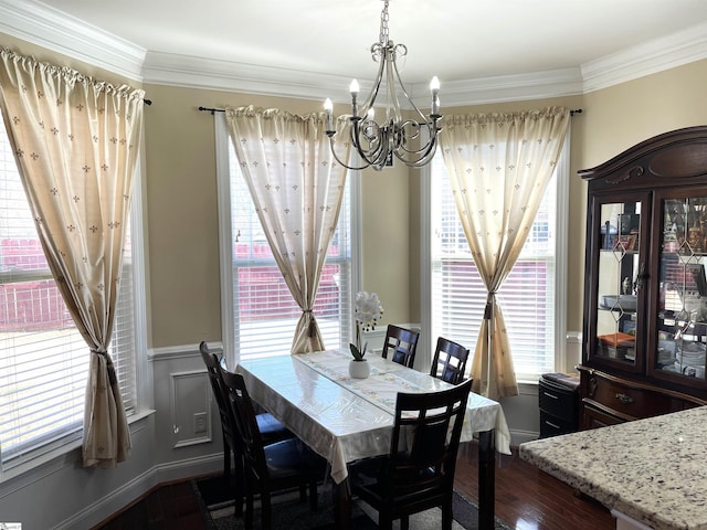 dining area featuring ornamental molding, a chandelier, a wainscoted wall, and dark wood finished floors