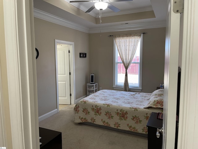 carpeted bedroom with ceiling fan, baseboards, ornamental molding, and a raised ceiling