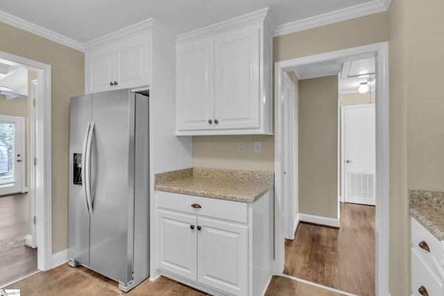 kitchen with crown molding, stainless steel fridge, visible vents, and white cabinets