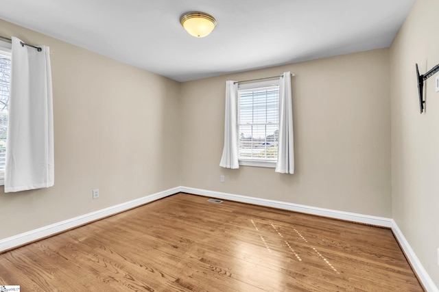 spare room with visible vents, baseboards, and wood finished floors