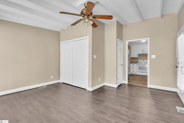 unfurnished bedroom featuring baseboards, ceiling fan, dark wood-type flooring, beamed ceiling, and a closet